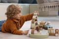 Boy playing with wooden Montessori stacking toys in his playroom. 