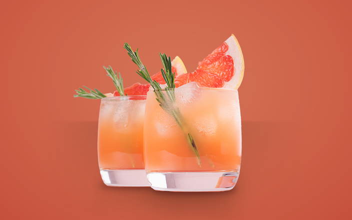 Two glasses of a grapefruit mocktail with sprigs of rosemary for Confetti's Virtual Mocktail Gift Set