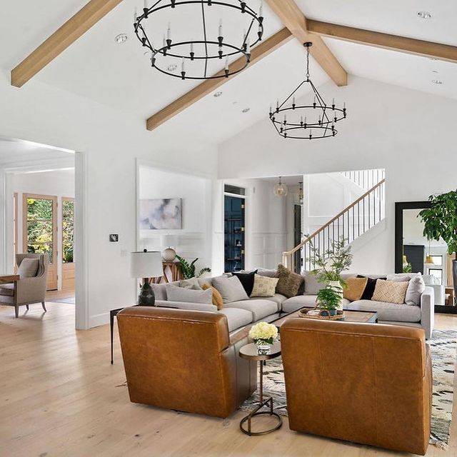 A family room with a high ceiling and gray and tan furniture.