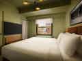 Modernes Hotelzimmer mit Kingsize-Bett, Flachbildfernseher, grün gestrichenen Wänden und Stadtblick.
