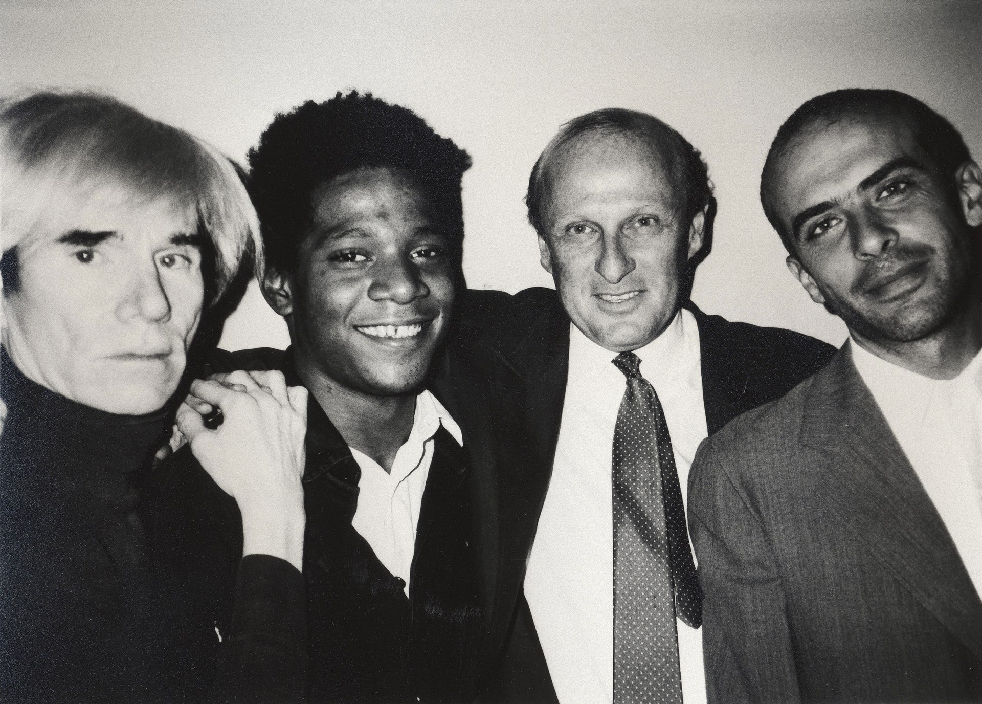Andy Warhol, Jean-Michel Basquiat, Bruno Bischofbeger and Fransesco Clemente smiling and looking at the camera.