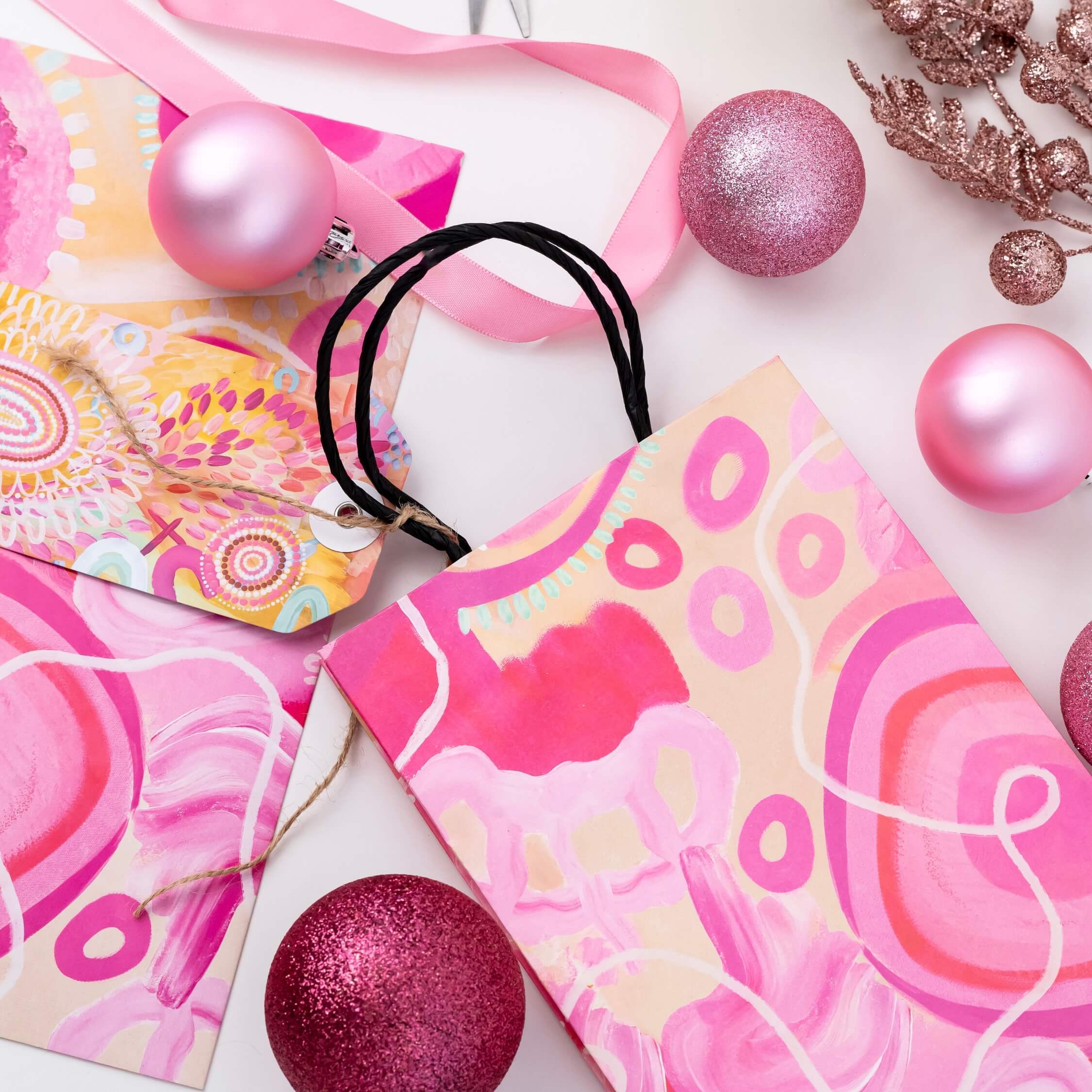 pink wrapping paper and bags with pinkchristmas decorations, scissors, and champagne