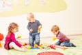 Three children playing with Montessori rattle toys and instruments in a playroom. 