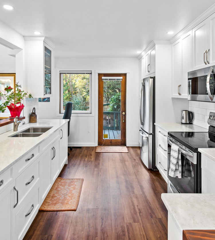 kitchen featuring natural light, refrigerator, microwave, electric range oven, white cabinetry, dark hardwood flooring, and light countertops