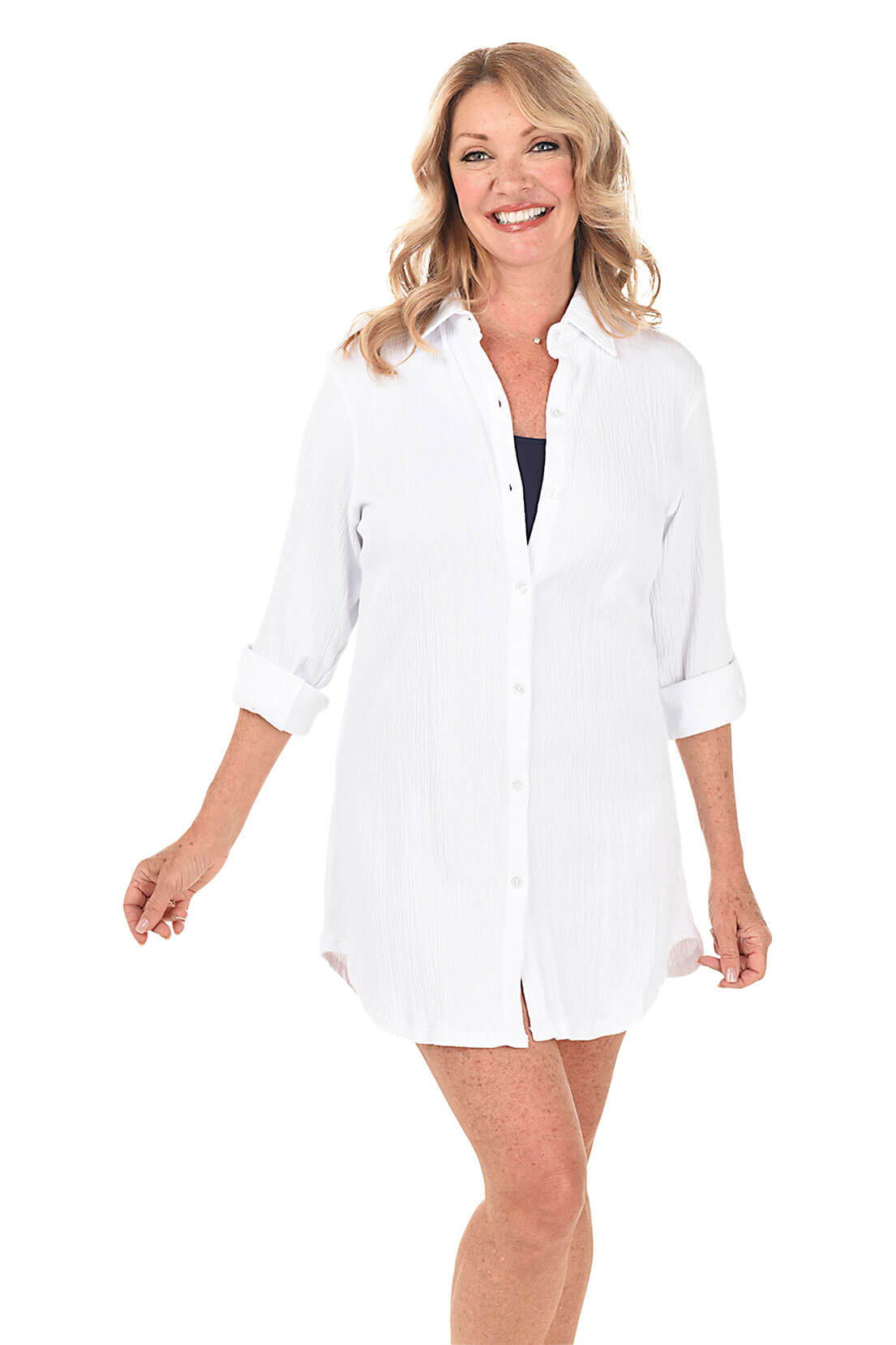 A woman wears a white oversized cover-up shirt over a navy blue tank bathing suit.