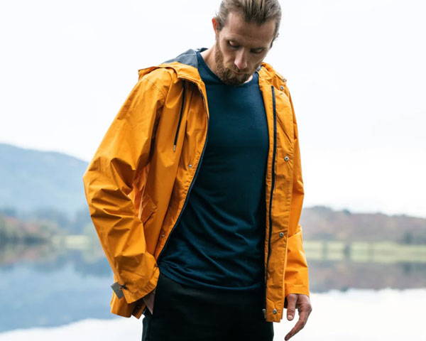 Man wearing technical outdoor jacket in orange from sustainable outdoor brand Meader Scotland