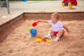 One year old child playing in the sand. 