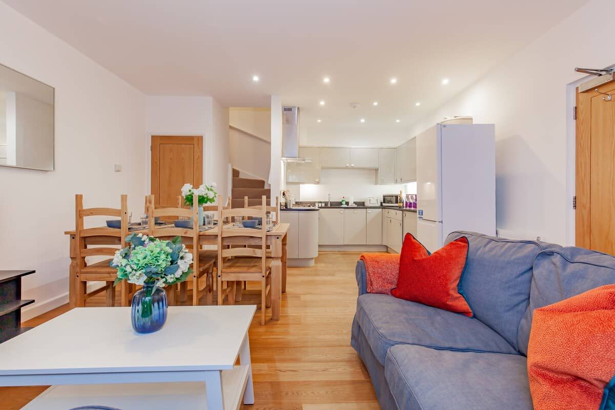 Living room facing in from the window side showing large sofa and kitchen in the top right corner