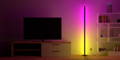 Eine Round Smart Lampe mit einem pinken und gelben Farbübergang neben einem Bücherregal und einen Fernseher