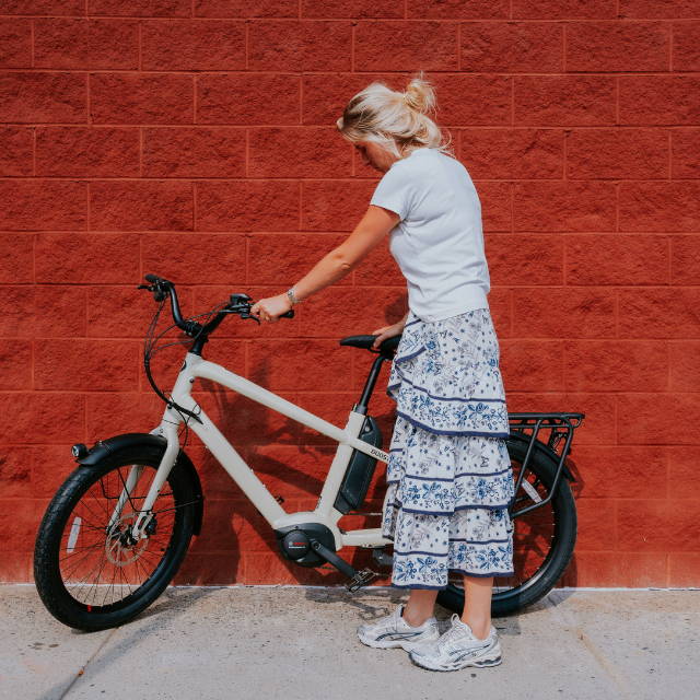 a woman in a dress standing next to a benno boost electric cargo bike