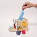 Woman's hand pulling a blue tissue from a panda shaped wooden box toy for babies.