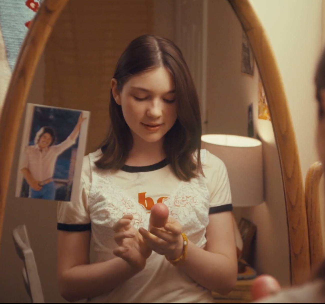 Young girl in front of mirror applying some Love's Baby Soft coologne on her.
