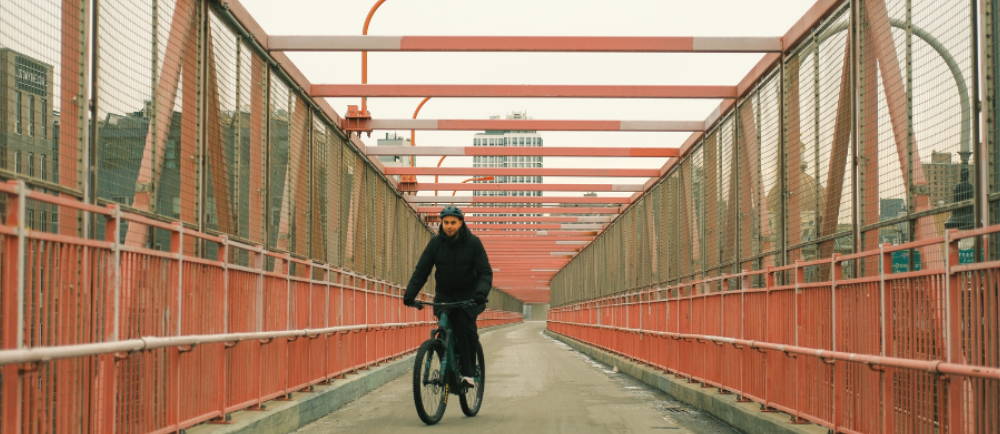 a man riding an electric bike across a bridge in New York City