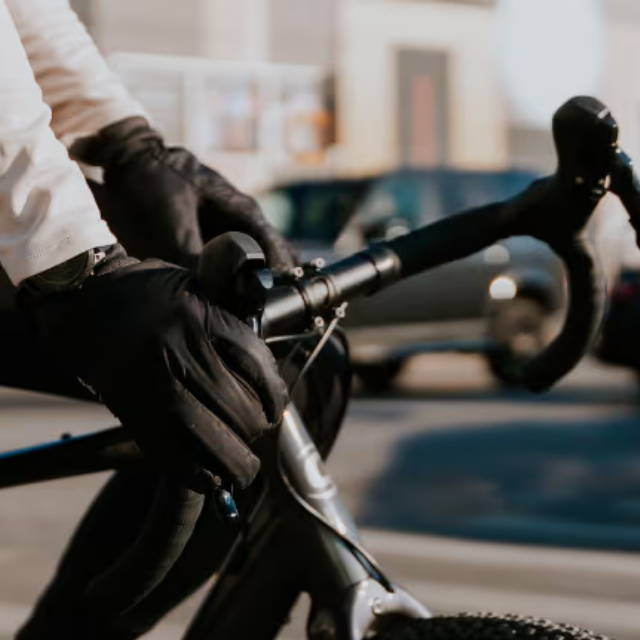 A person in black gloves on an electric road bike