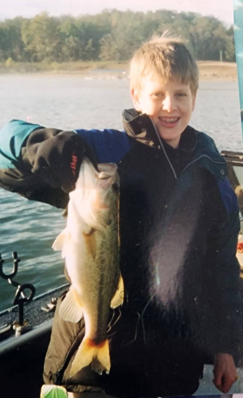 A young angler holding a fish on a boat