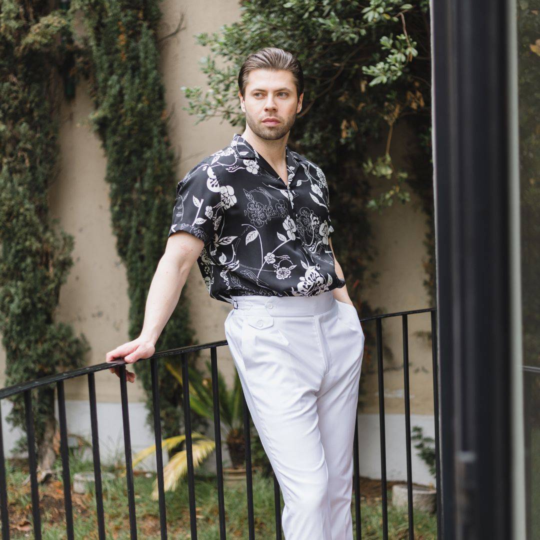 model standing on a balcony while wearing white high rise pants and a short sleeve gothic floral silk shirt from 1000 kingdoms