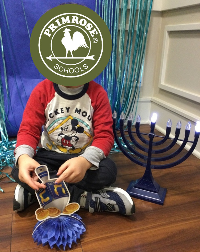 child sitting with dreidel and menorah 