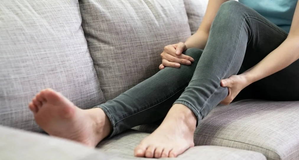 Woman massages her legs because of pain from long standing during working hours.