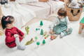 Toddlers playing with wooden animals and trees. 