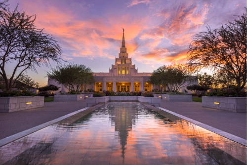 Phoenix Temple standing behind a reflection pool with orange and purple clouds. 