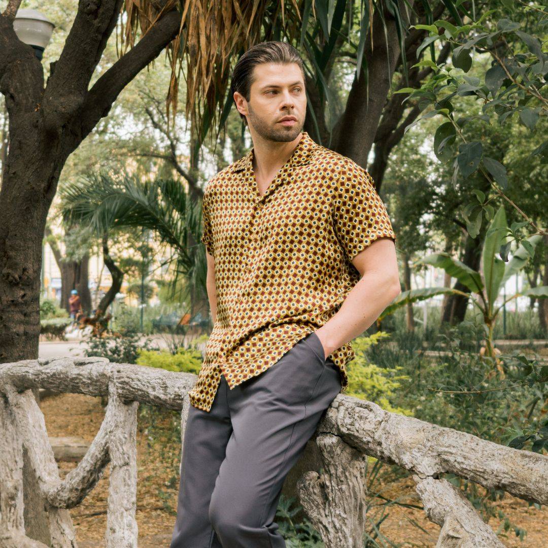 model standing in the park wearing grey pants and a short sleeve gold bowling silk shirt from 1000 kingdoms