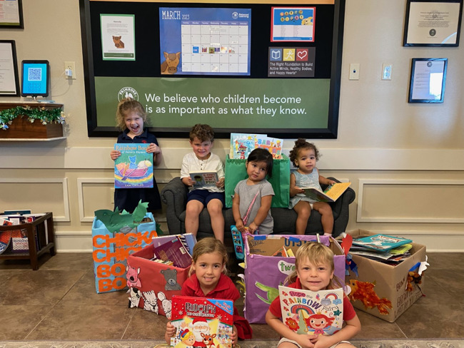 Children posing with donated books for the book drive