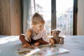 Toddler exploring a Montessori picture book independently during quiet reading time with stuffed toy nearby
