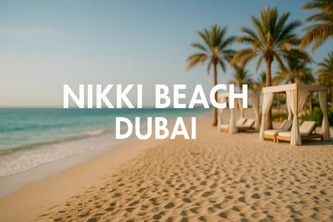 Sunny beach at Nikki Beach Dubai with soft sand, footprints, gentle waves, palm trees, and white cabanas with lounge chairs.