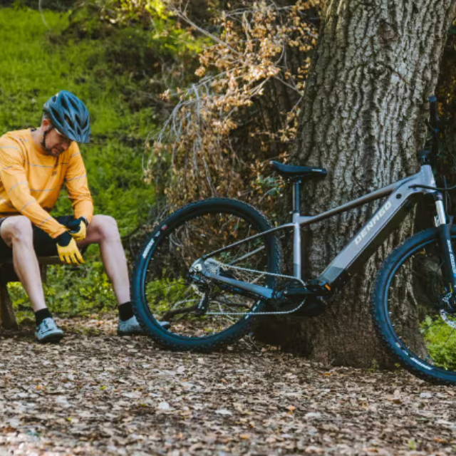 a man in the forest next to an electric mountain bike