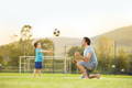 Father and son playing catch on a football field.