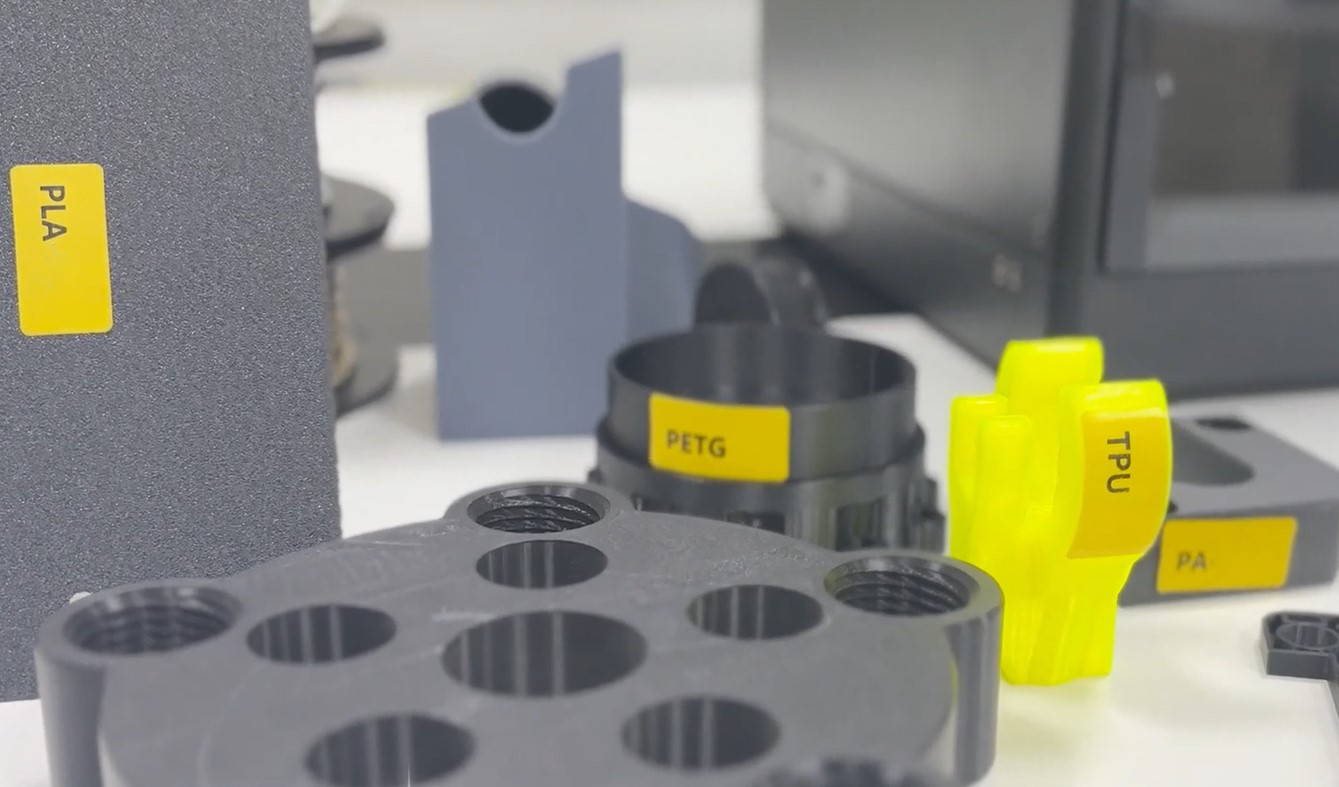 3D printed bracket in silver filament showing Dremel logo, printed on Dremel 3D45 printer