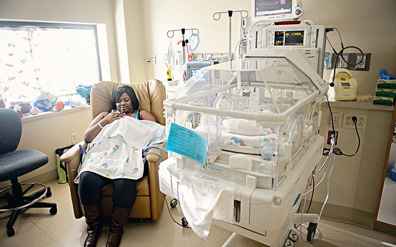 black nicu mother holding preemie baby next to window, for good NICU photography lighting