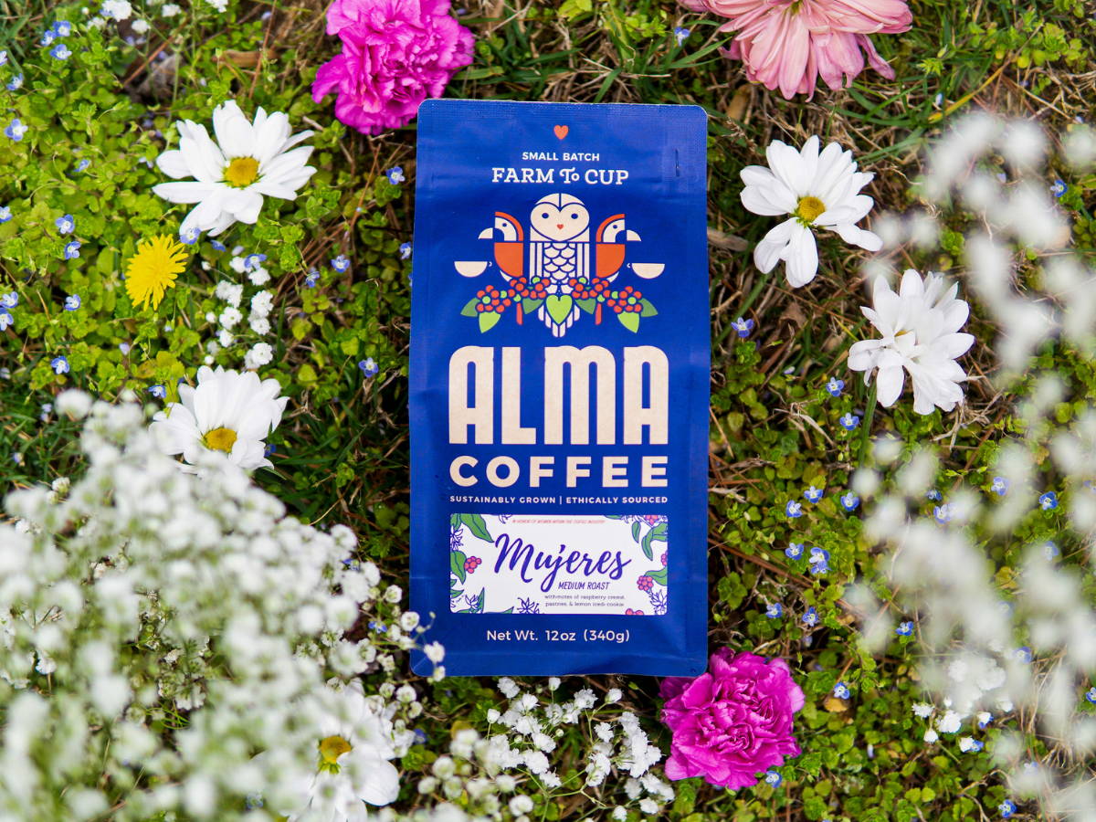 Bag of Alma Coffee's Mujeres Roast in a flower patch