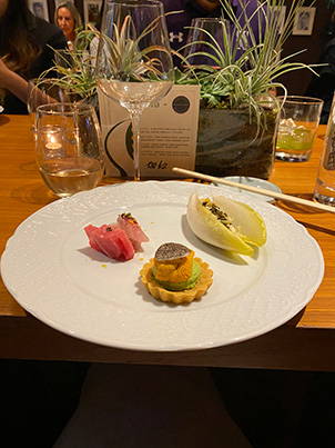 A dinner plate with Crab Salad in endive shell, tart with uni, and sashimi