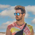 Man hiding his red eyes on the beach by wearing sunglasses