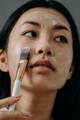 Woman rubbing on a face mask with a face brush for dewy skin
