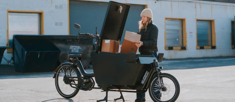 a woman loading boxes into an Urban Arrow front loader electric cargo bike