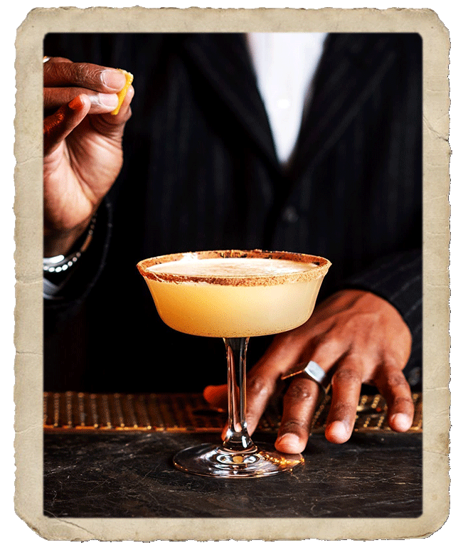 Bartender squeezing orange peel over tequila cocktail