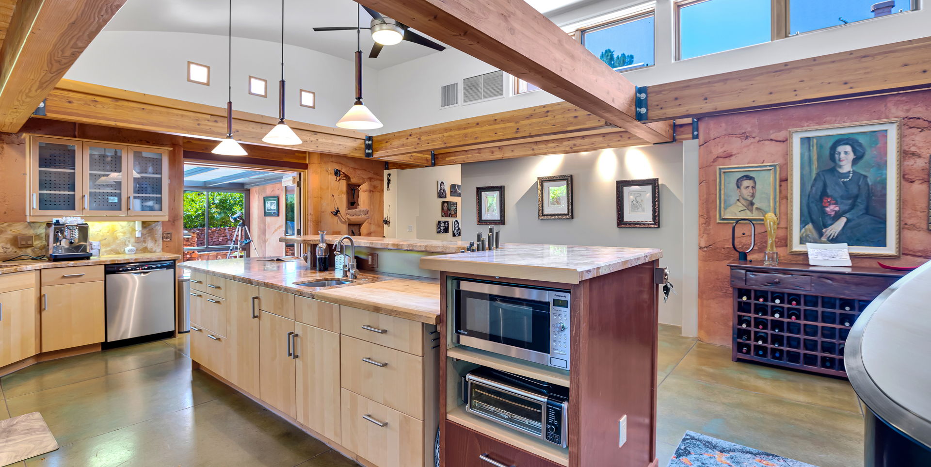 kitchen featuring beamed ceiling, natural light, stainless steel dishwasher, microwave, pendant lighting, light tile flooring, and light stone countertops