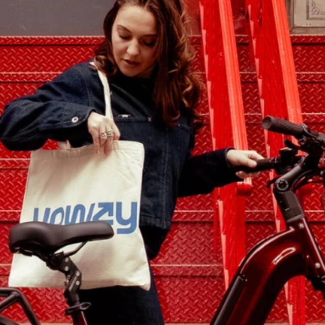 a woman standing next to an electric city while looking into an upway handbag, in front of red steps and a red building