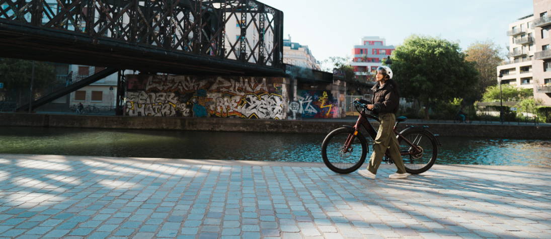 Femme poussant son vélo électrique acheté à petit prix.