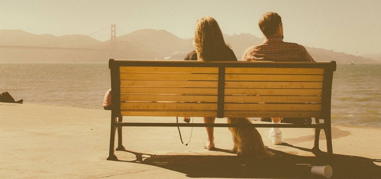 Paar sitzt nebeneinander auf einer Bank und schaut auf Golden Gate Bridge