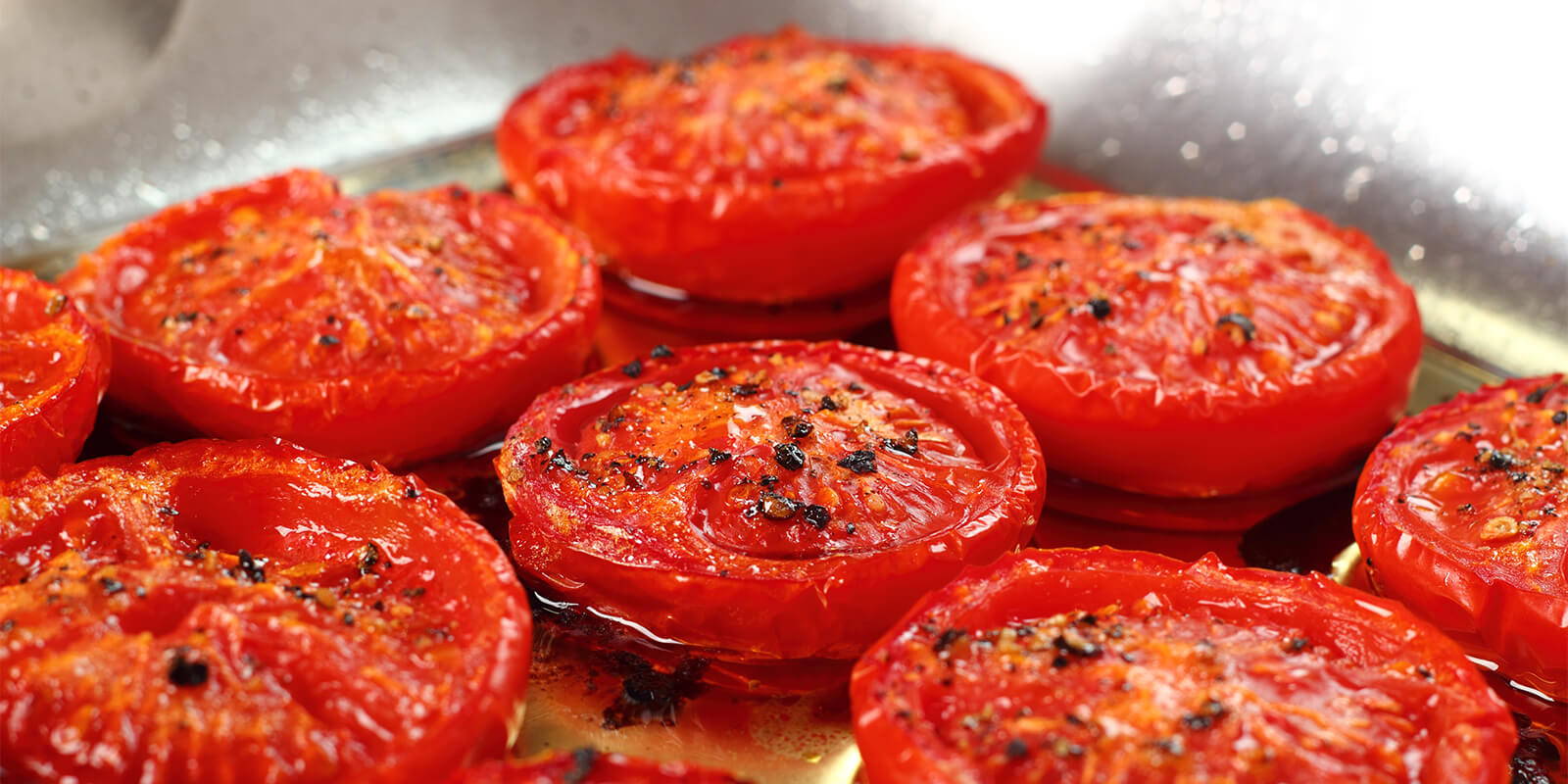 Roasted Tomatoes in a pan with oil.