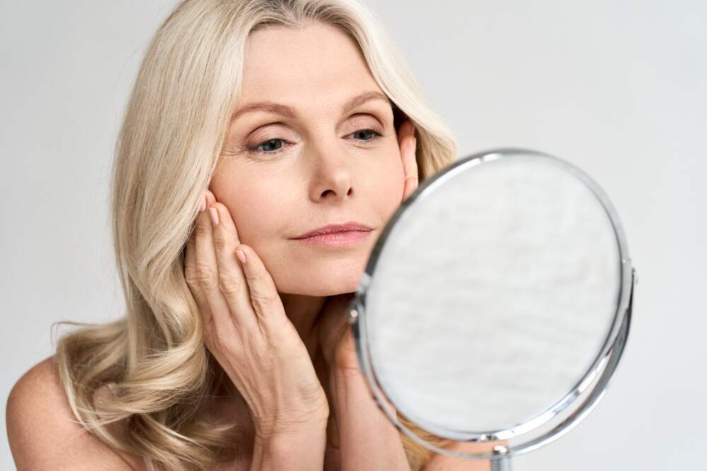 woman looking at her skin and lack of collagen in a mirror