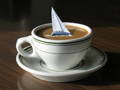 A small mug of espresso with a little sailor boat floating on the coffee