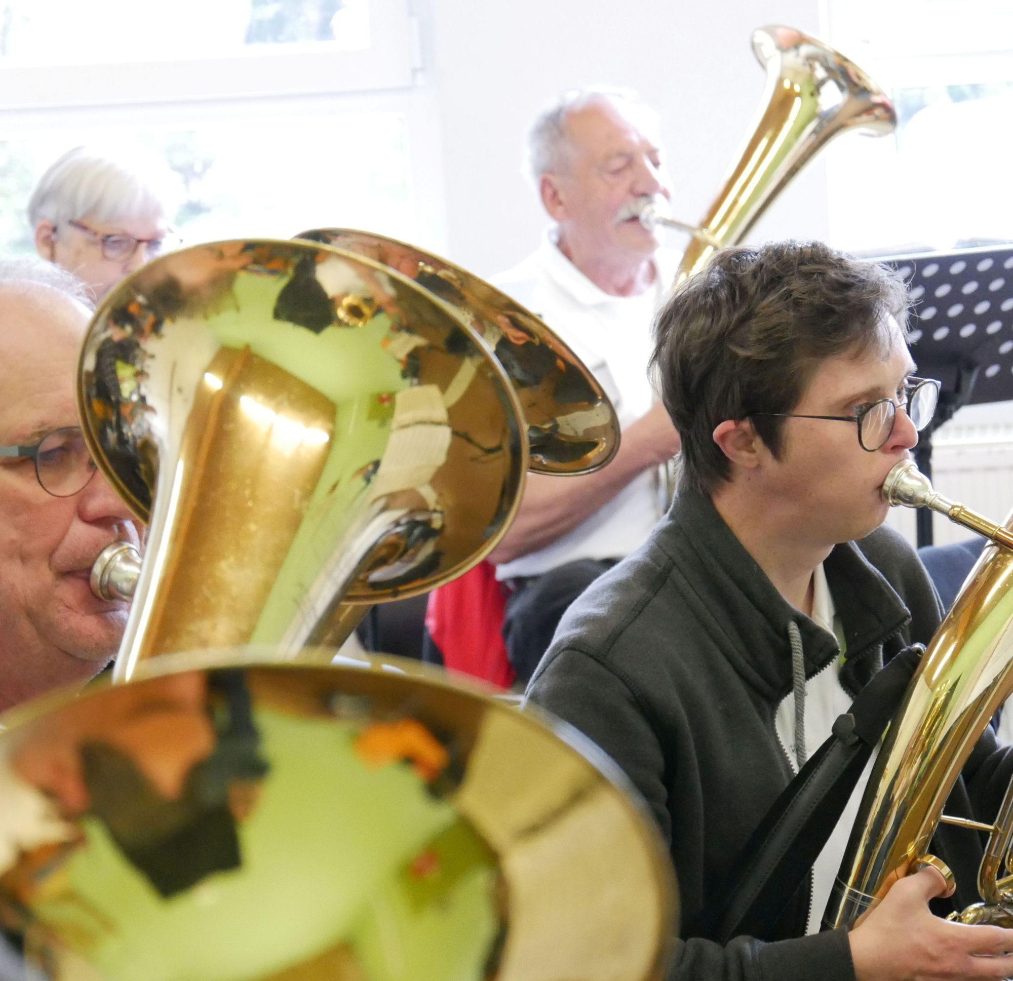 Einige Männer mit und ohne Behinderung musizieren gemeinsam auf Tenorhörnern. 