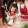 Little girl helping her mom in baking the Christmas cookies. 