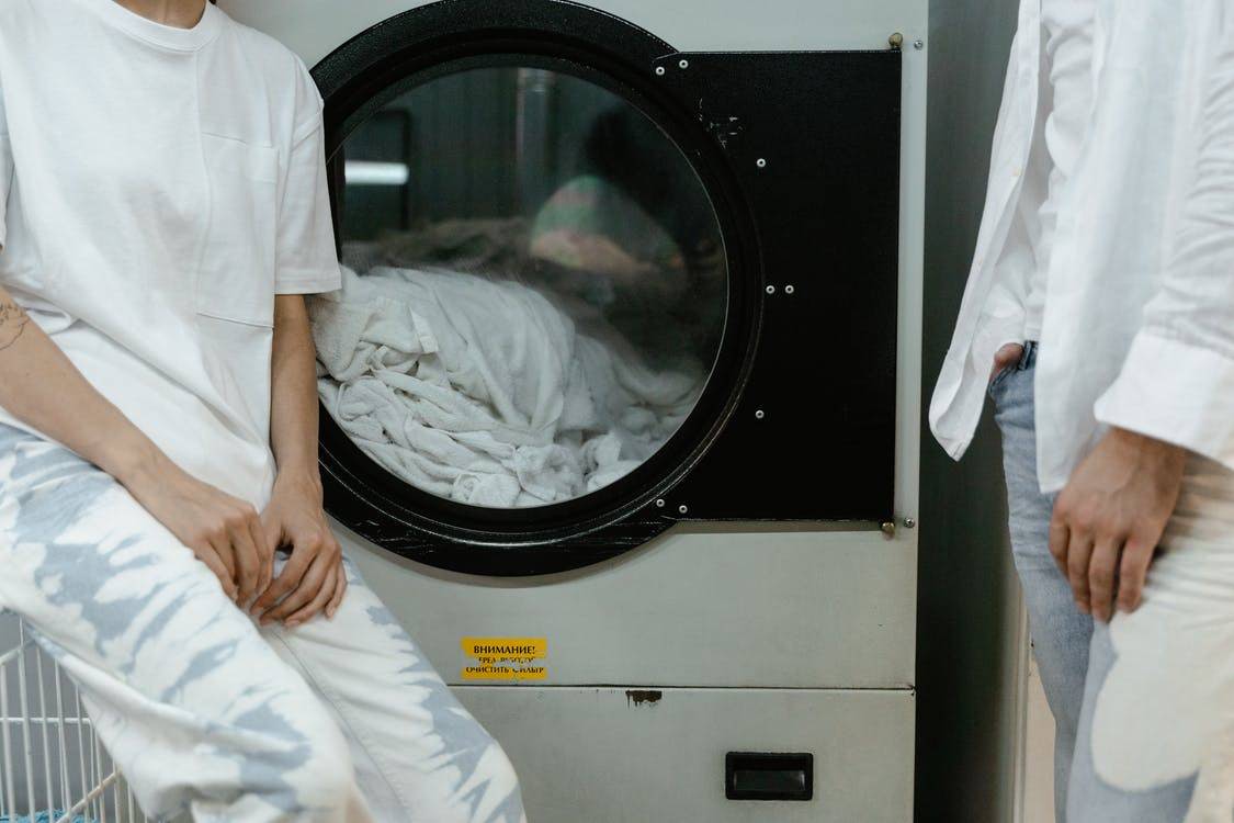 People wearing white tops near a washing machine