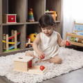 Little girl playing with her Montessori Object Permanence Box. 