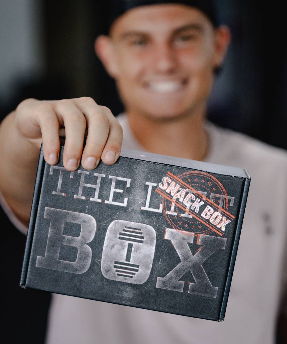Women holding a Snack Box subscription from the Lift Box. Badge in lower left corner that reads "2023 best fitness subscription box" with a five star icon from My Subscription Addiction.